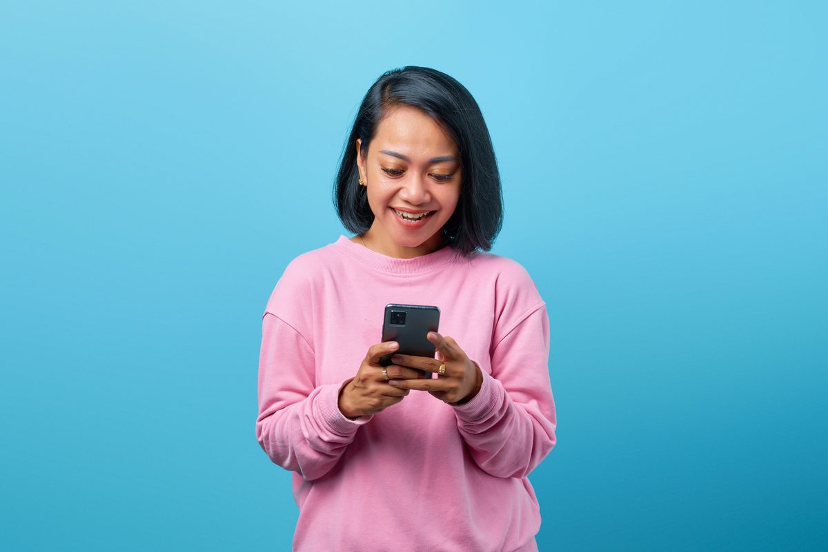 Mulher sorrindo enquanto olha para a tela do celular